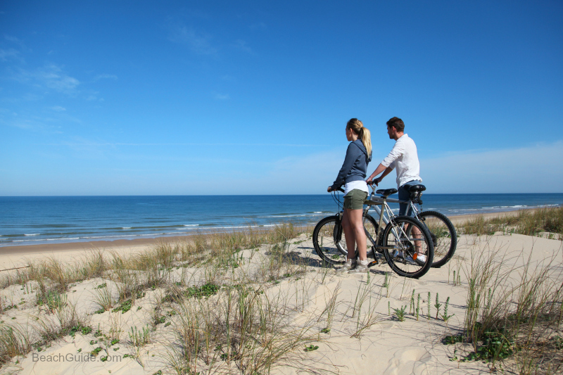 Couple enjoying a winter bike ride on Hwy 30a beaches in Florida.
