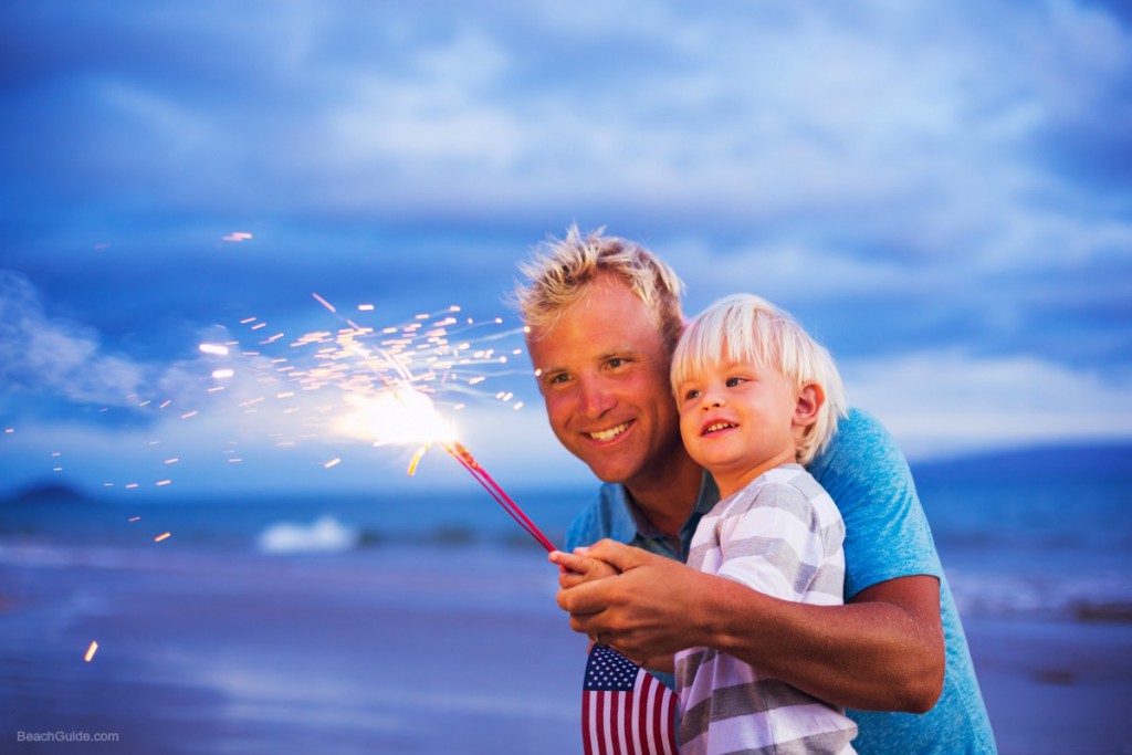 Father and son lighting sparklers on the beach at sunset