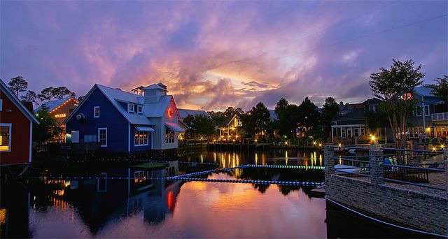 Evening shot of Sandestin's Village of Baytowne Wharf with lights reflected in the waters of the bay