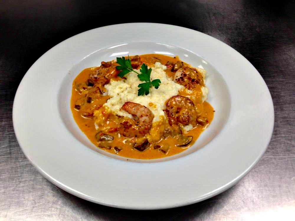 Shrimp and grits served on a white plate at 723 Whiskey Bravo restaurant in Seagrove Beach, Florida
