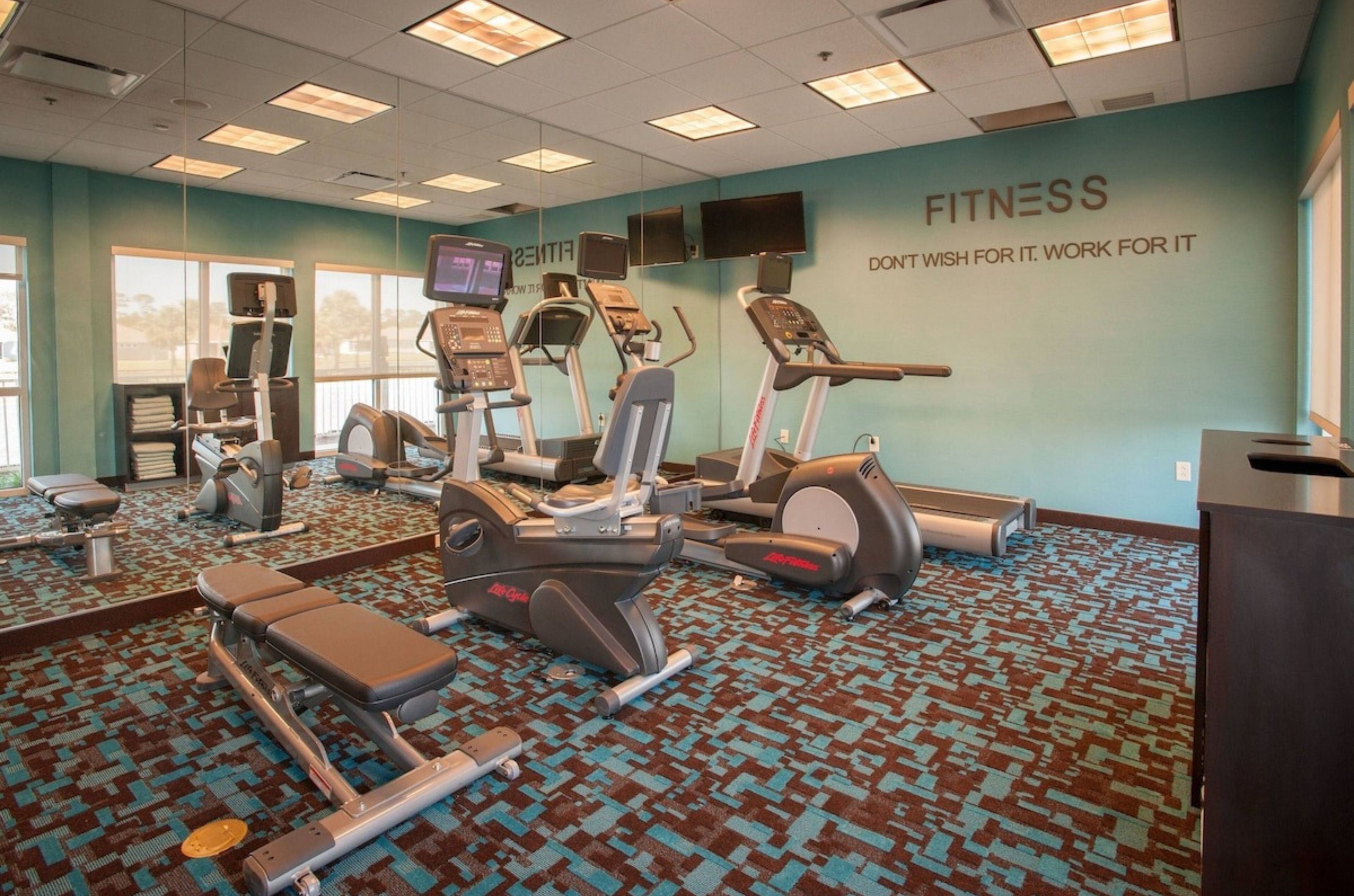 Workout equipment in front of a mirrored wall in the gym at Fairfield Inn and Suites 
